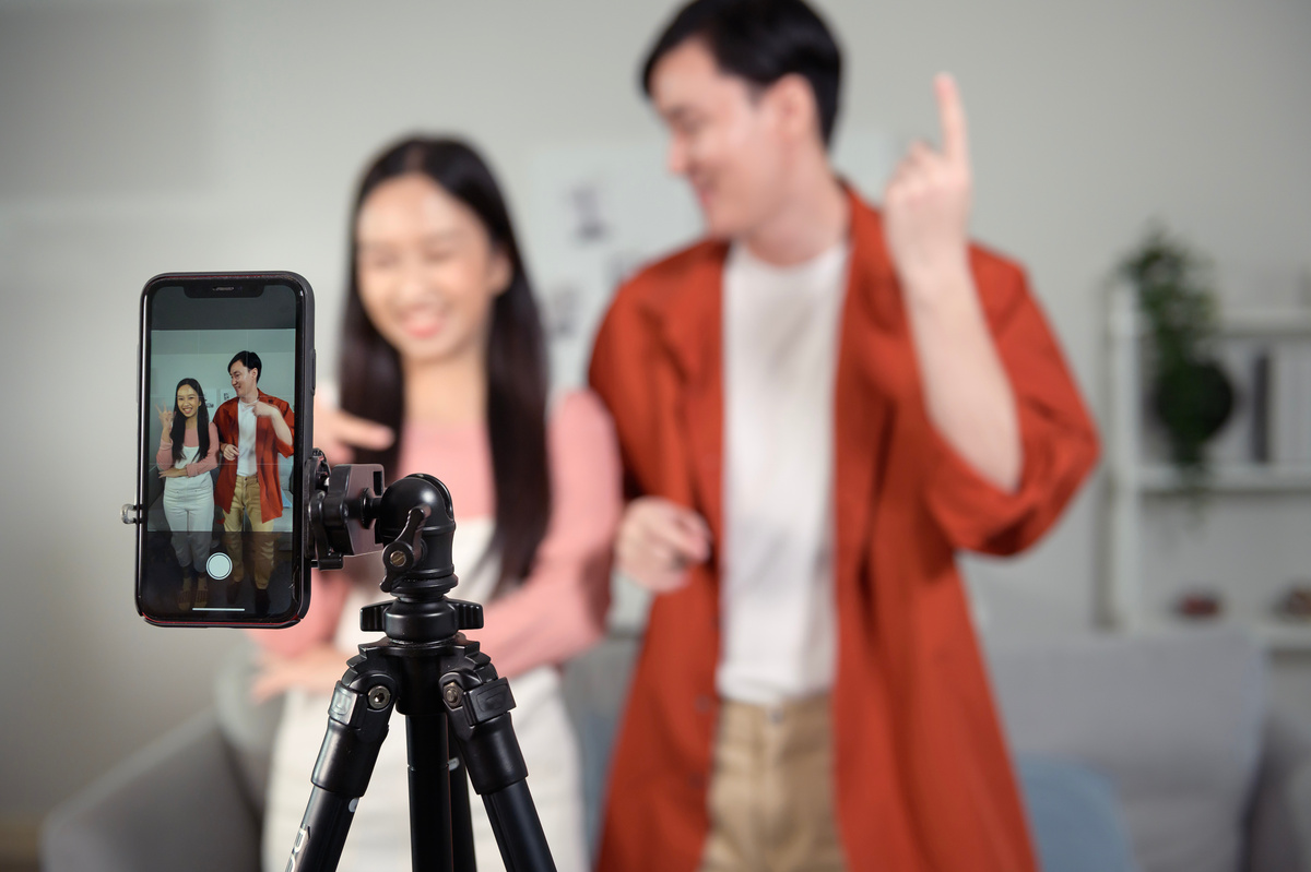 Asian young couple tiktokers are making video dancing  via smartphone together,  share video content on social media.