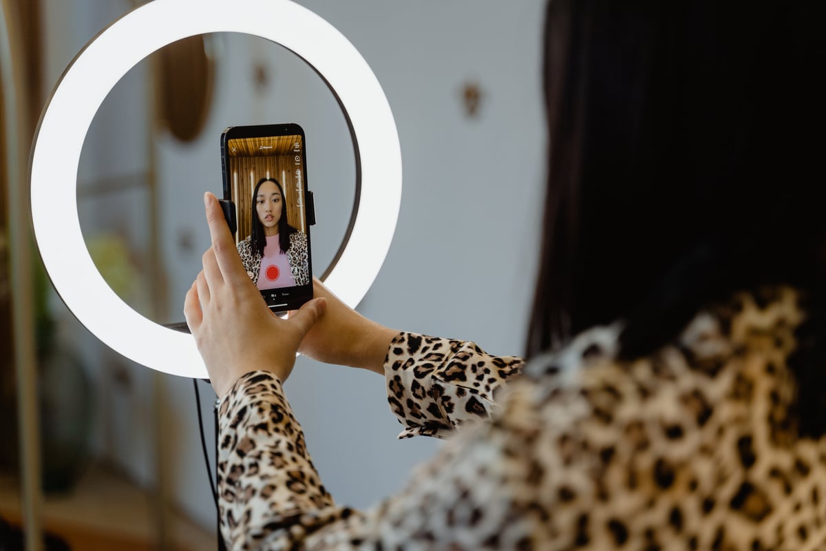 A Woman Using Smartphone and Ring Light